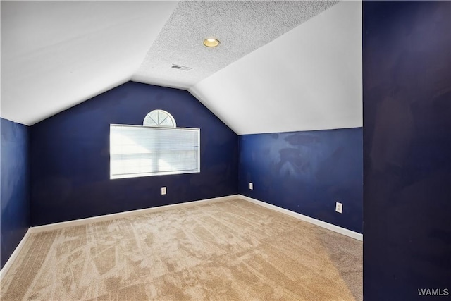 bonus room featuring lofted ceiling, a textured ceiling, visible vents, baseboards, and carpet