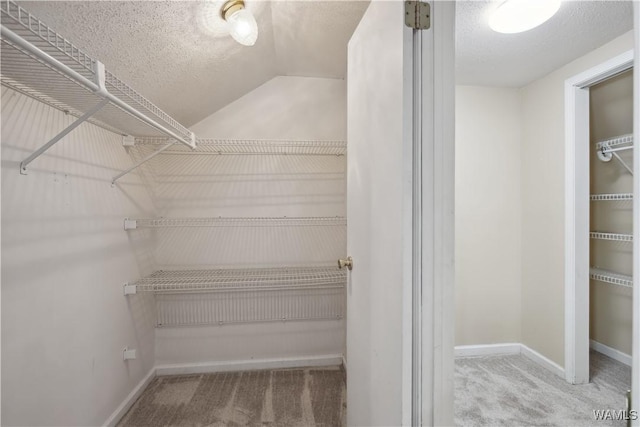 walk in closet featuring carpet floors and vaulted ceiling