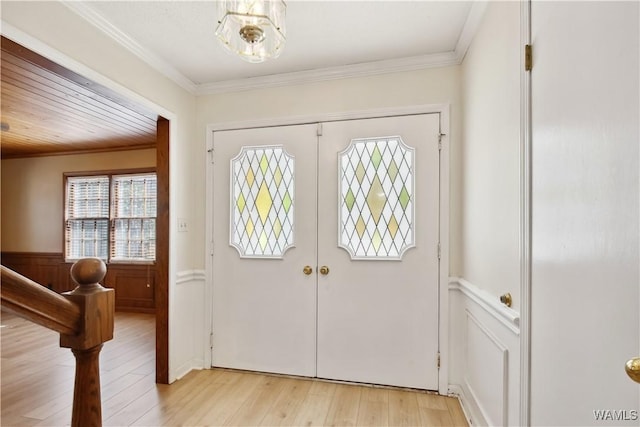 entryway with ornamental molding, french doors, and light wood-type flooring