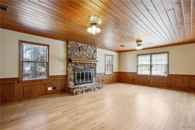 unfurnished living room with a healthy amount of sunlight, a wainscoted wall, and wood ceiling