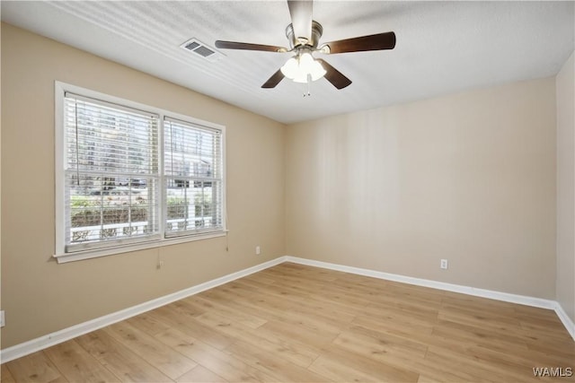 spare room featuring baseboards, a ceiling fan, visible vents, and light wood-style floors