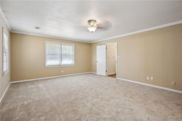 carpeted empty room featuring a textured ceiling, baseboards, visible vents, and crown molding