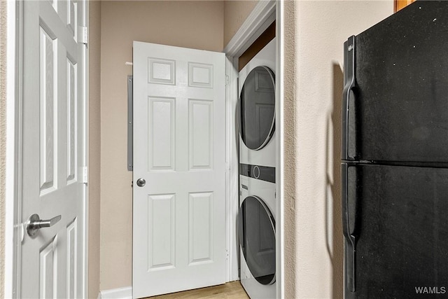 washroom with stacked washer and dryer, light wood-style flooring, and laundry area