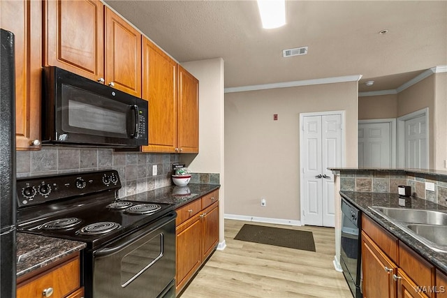 kitchen with light wood-style flooring, visible vents, decorative backsplash, black appliances, and brown cabinetry