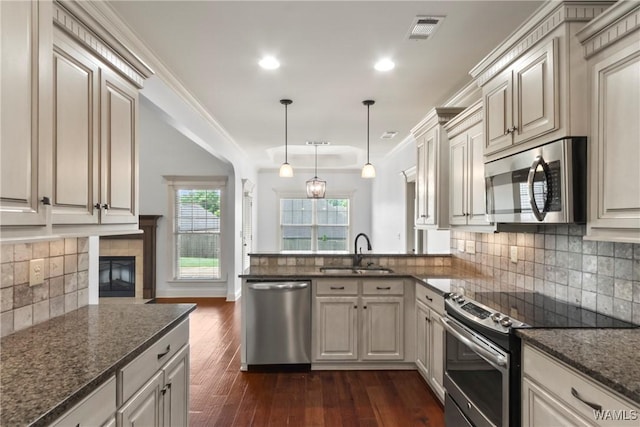 11542 Woodford St, Northport, AL 35475 - kitchen with appliances with stainless steel finishes, a sink, a peninsula, tasteful backsplash, and dark wood-style floors