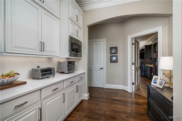 1231 Diamond Point Cir, Tuscaloosa, AL 35406 - kitchen with stainless steel microwave, dark wood finished floors, a toaster, arched walkways, and white cabinetry
