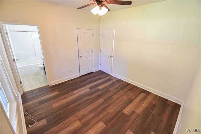 unfurnished bedroom featuring connected bathroom, ceiling fan, and dark wood-type flooring