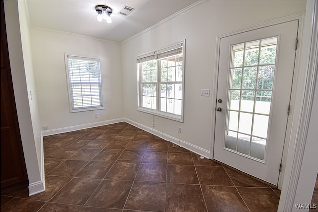 doorway to outside with dark tile patterned floors, ornamental molding, and a wealth of natural light