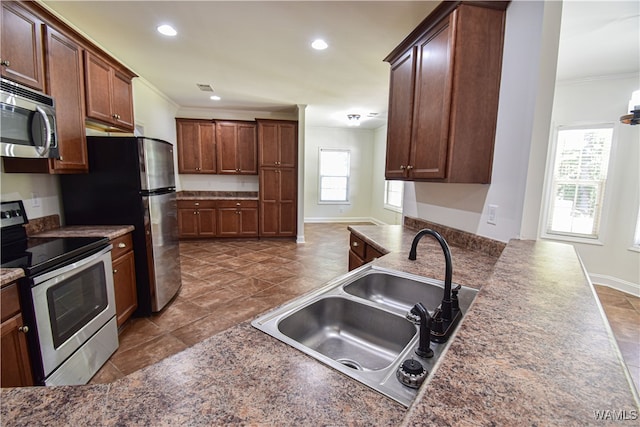 kitchen with ornamental molding, sink, and appliances with stainless steel finishes