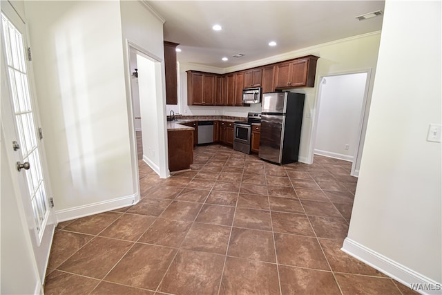 kitchen with sink, ornamental molding, dark tile patterned flooring, and appliances with stainless steel finishes