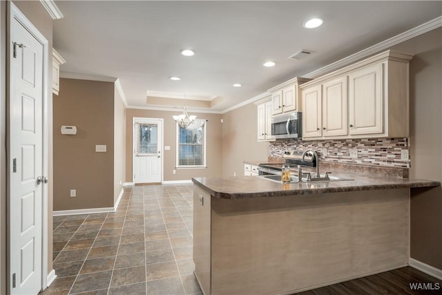 kitchen featuring ornamental molding, appliances with stainless steel finishes, kitchen peninsula, and cream cabinets