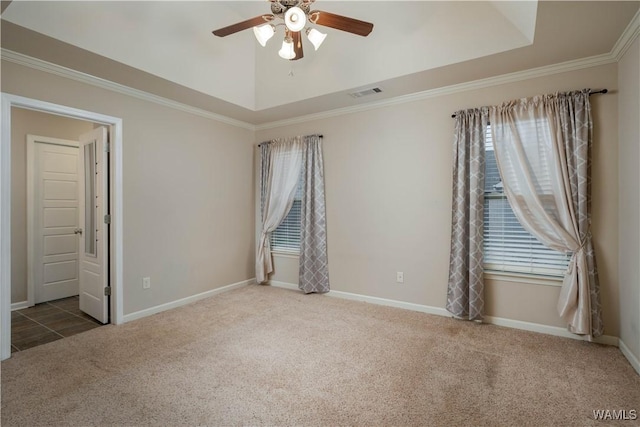 spare room featuring a raised ceiling, crown molding, carpet floors, and ceiling fan