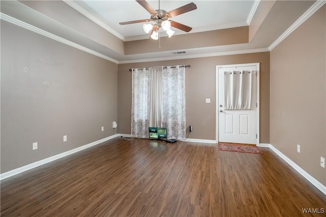 spare room featuring a tray ceiling, dark wood-type flooring, ornamental molding, and ceiling fan