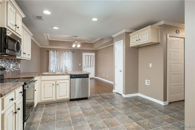 kitchen with sink, crown molding, stainless steel appliances, cream cabinets, and a tray ceiling