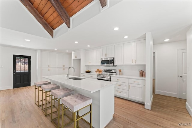 kitchen with appliances with stainless steel finishes, sink, white cabinetry, a breakfast bar area, and an island with sink