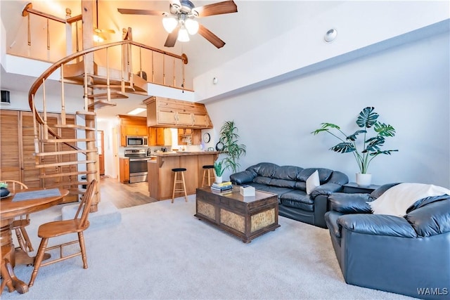 living room with a high ceiling, light carpet, and ceiling fan