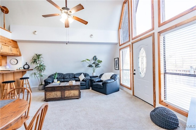 living room featuring ceiling fan, light colored carpet, a towering ceiling, and a wealth of natural light