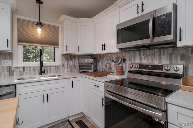 kitchen featuring white cabinets, appliances with stainless steel finishes, decorative backsplash, and sink