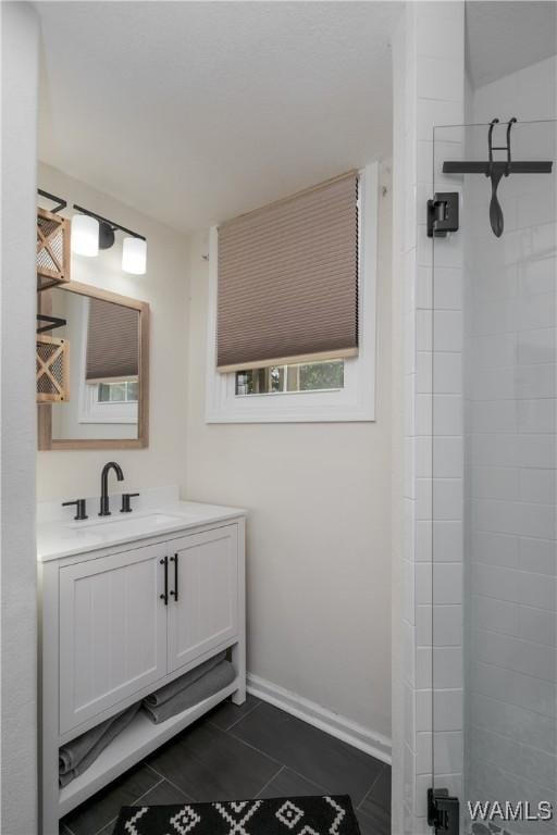 bathroom featuring a tile shower, vanity, and tile patterned floors