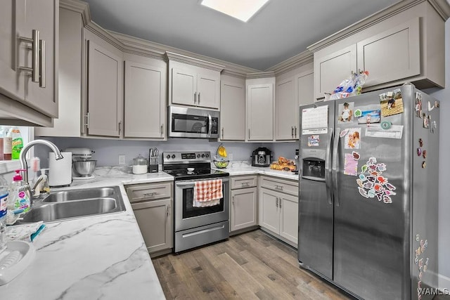 19026 Eastern Valley Rd, West Blocton, AL 35184 - kitchen featuring appliances with stainless steel finishes, a sink, wood finished floors, gray cabinetry, and light stone countertops