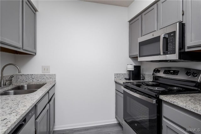 1009 12th St Unit 19, Tuscaloosa, AL 35401 - kitchen with appliances with stainless steel finishes, gray cabinetry, wood finished floors, and light stone counters