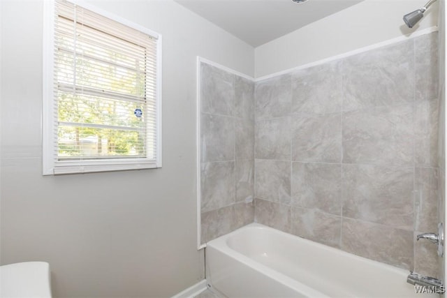 bathroom with toilet, tiled shower / bath, and a healthy amount of sunlight