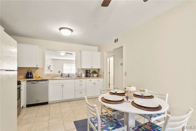 kitchen featuring appliances with stainless steel finishes, tasteful backsplash, sink, light tile patterned floors, and white cabinets