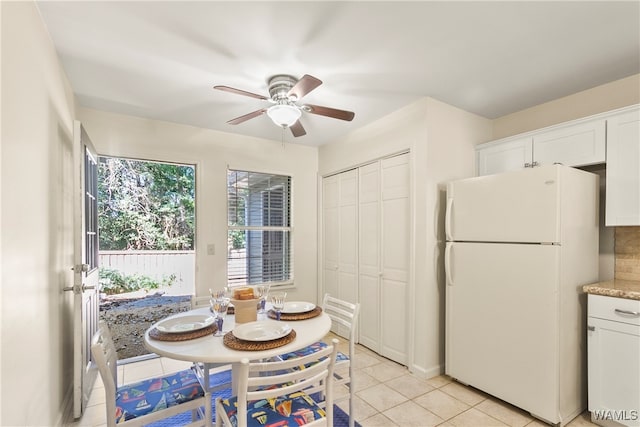 kitchen with backsplash, ceiling fan, light tile patterned floors, white refrigerator, and white cabinetry