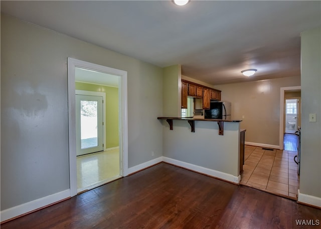 kitchen with a kitchen bar, a wealth of natural light, wood-type flooring, and fridge