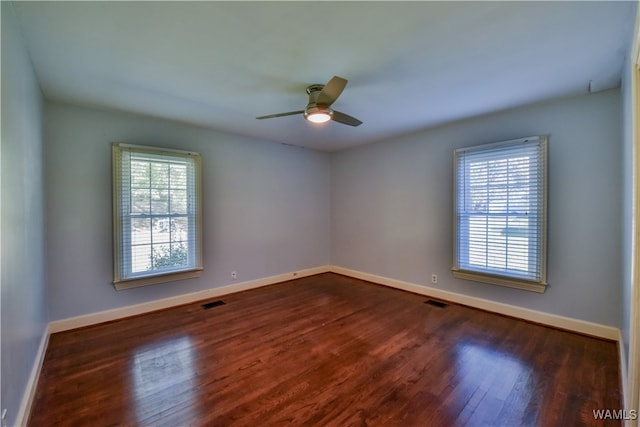 empty room featuring dark hardwood / wood-style floors, ceiling fan, and a wealth of natural light