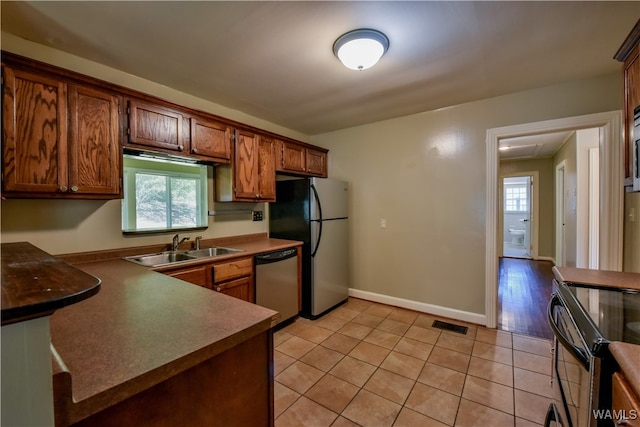 kitchen with appliances with stainless steel finishes, light hardwood / wood-style floors, and sink