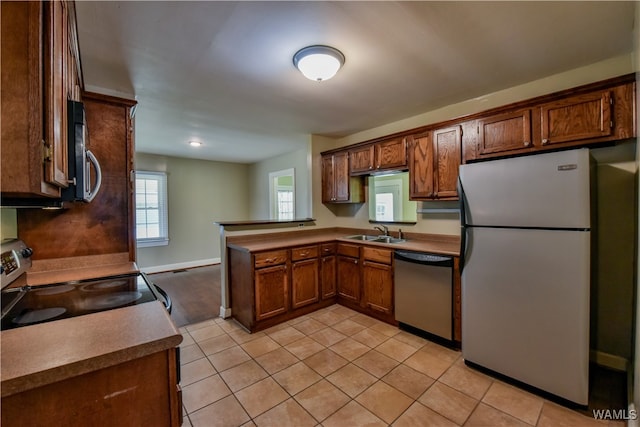 kitchen featuring kitchen peninsula, sink, light tile patterned floors, and stainless steel appliances