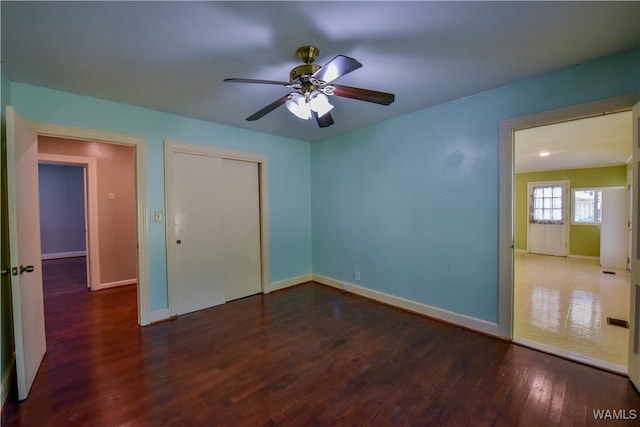 unfurnished bedroom featuring a closet, ceiling fan, and dark wood-type flooring