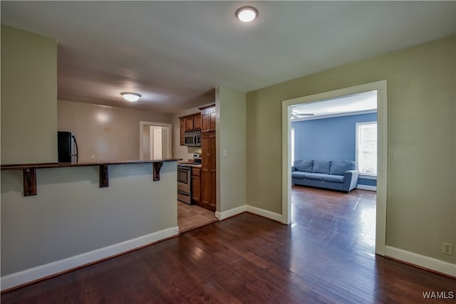 kitchen with a breakfast bar, dark hardwood / wood-style flooring, kitchen peninsula, and appliances with stainless steel finishes