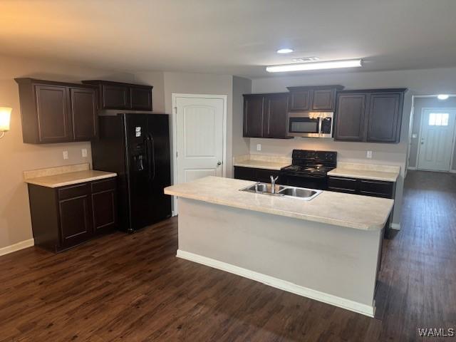 kitchen with black appliances, a sink, dark wood-style floors, light countertops, and baseboards