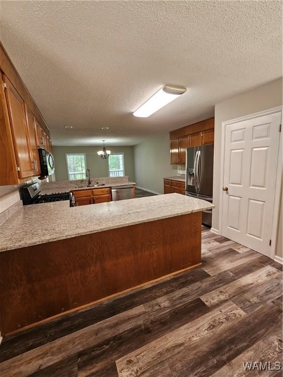14541 Keenes Mill Rd, Coaling, AL 35453 - kitchen featuring appliances with stainless steel finishes, a peninsula, dark wood-type flooring, a textured ceiling, and a chandelier