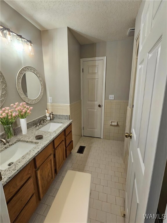 14541 Keenes Mill Rd, Coaling, AL 35453 - full bath featuring tile walls, tile patterned flooring, wainscoting, double vanity, and a textured ceiling