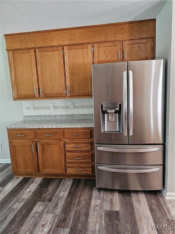 14541 Keenes Mill Rd, Coaling, AL 35453 - kitchen featuring stainless steel refrigerator with ice dispenser, brown cabinetry, dark wood-style floors, decorative backsplash, and a textured ceiling