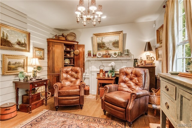 living area featuring wooden walls, light hardwood / wood-style flooring, and a notable chandelier