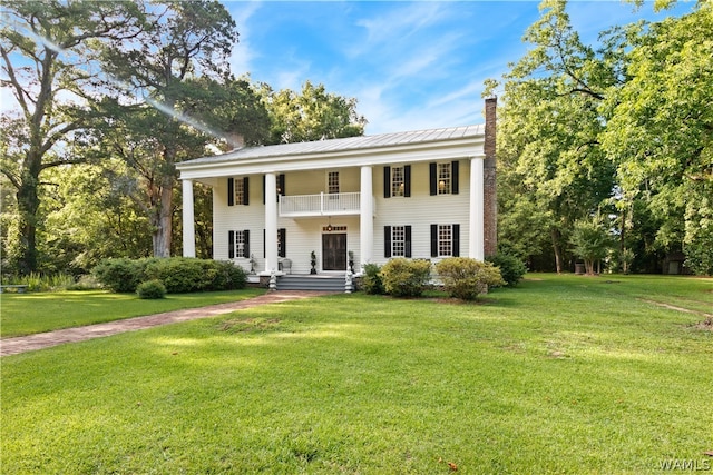 greek revival house with a balcony and a front lawn