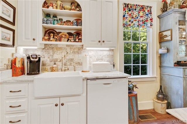 kitchen with tasteful backsplash, white cabinets, light stone countertops, and white dishwasher