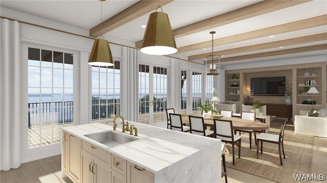 kitchen with light wood-style flooring, a sink, beam ceiling, decorative light fixtures, and a kitchen island with sink