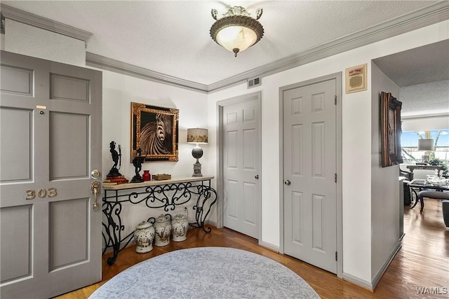 interior space with visible vents, ornamental molding, a textured ceiling, wood finished floors, and baseboards