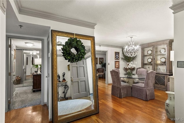 interior space with a textured ceiling, wood finished floors, and crown molding