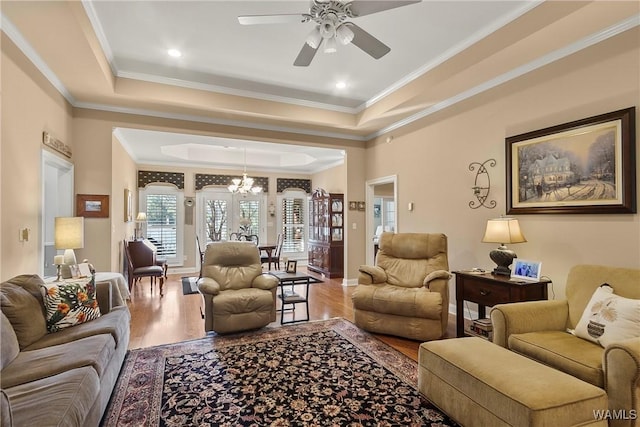 living room featuring ceiling fan with notable chandelier, a tray ceiling, and hardwood / wood-style floors