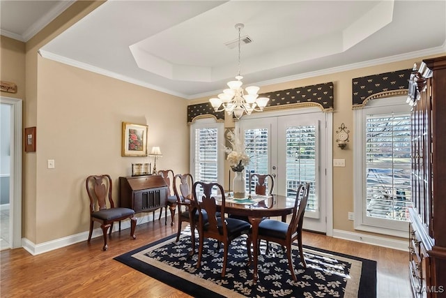 dining room featuring a healthy amount of sunlight, a tray ceiling, and hardwood / wood-style floors