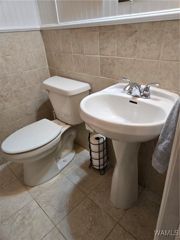 bathroom featuring tile patterned floors, toilet, and tile walls