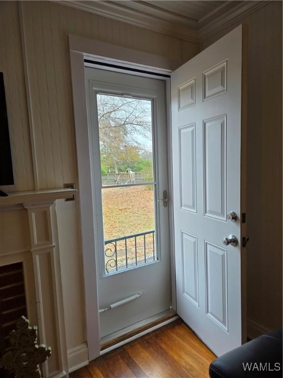 doorway with wood-type flooring and ornamental molding