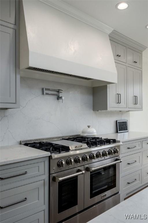 1901 Point Clear Rd, Tuscaloosa, AL 35406 - kitchen featuring decorative backsplash, ornamental molding, light stone countertops, custom exhaust hood, and double oven range