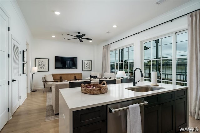 kitchen with dishwasher, light hardwood / wood-style flooring, sink, ceiling fan, and a center island with sink